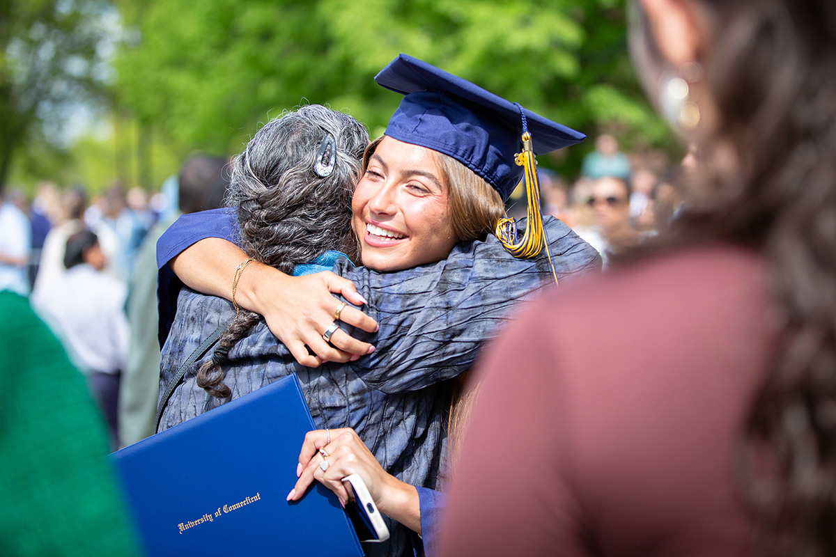 A graduate receives a hug from a loved one.