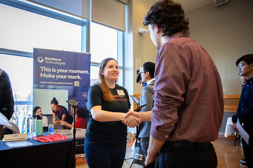 A student shakes a recruiter's hand at an internship fair.