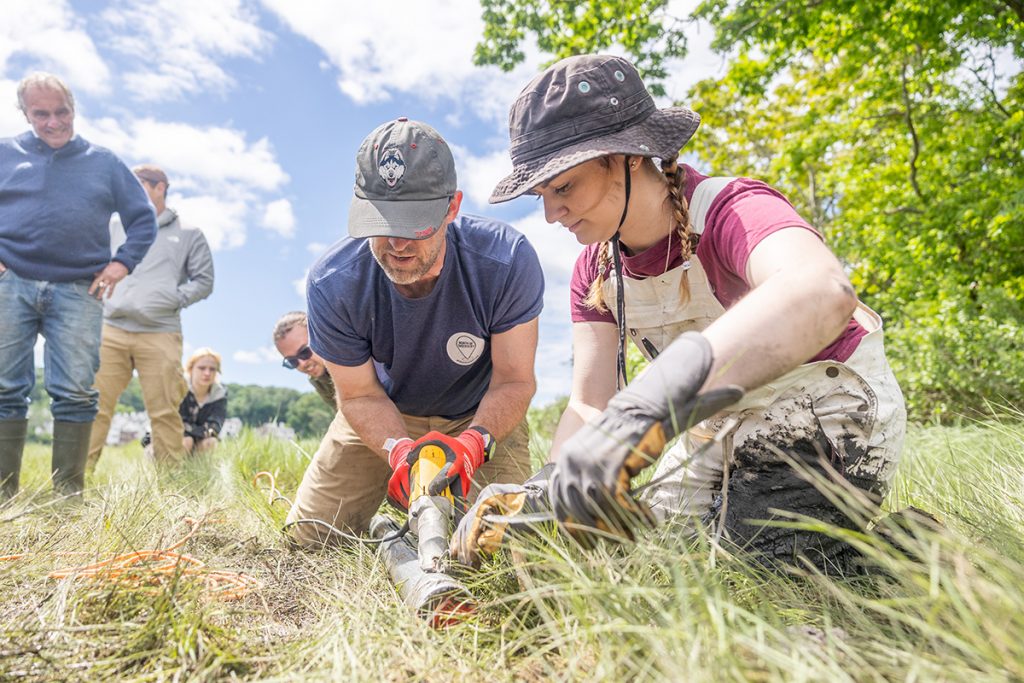 A professor and student work to cut the pipe of the soil cores their team collected.