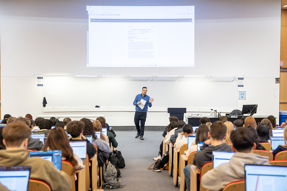 A professor stands in front of a crowded lecture hall.