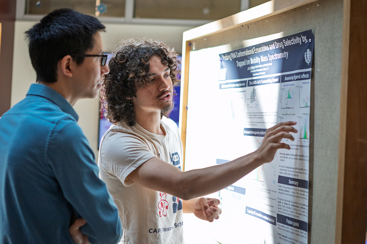 A student points to his research poster.